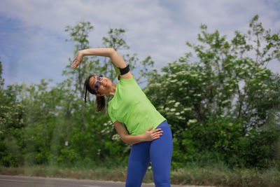 Full length of young woman exercising on field