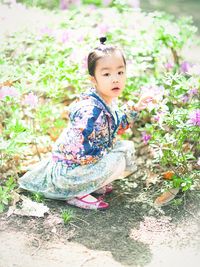 Portrait of girl crouching on field