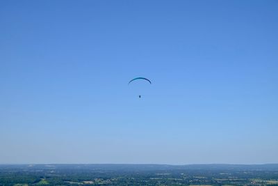 Person paragliding against clear blue sky