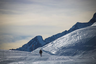 Man walking on snowcapped mountain against sky