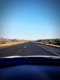 Road against clear blue sky seen through car windshield