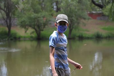 Portrait of boy wearing mask standing by lake