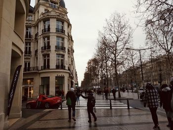 People walking on street amidst buildings in city