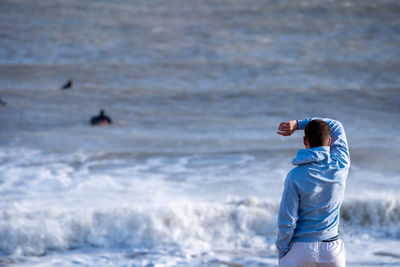 Rear view of a young man on the beach at rivedoux watching surfers riding the waves, ile de re, 