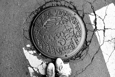 Low section of person standing on manhole