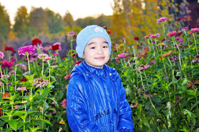 Portrait of cute girl wearing warm clothing standing against plants