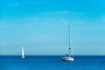 Sailboat sailing on sea against blue sky