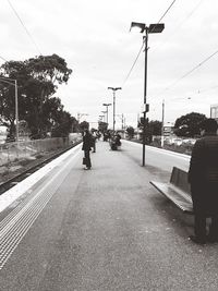 Man walking on railroad track against sky