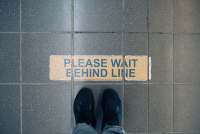 Top down view of person waiting in line, focusing on shoes.