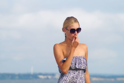 Young woman wearing sunglass by sea against sky