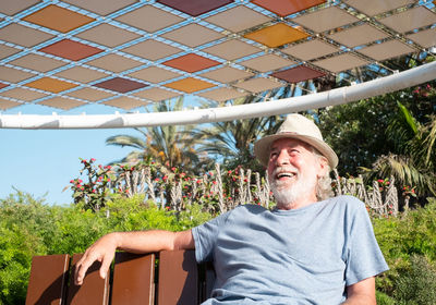 Happy man sitting on chair against plants