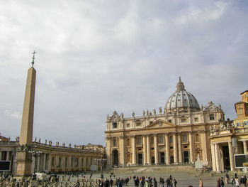 Tourists on top of historic building against sky