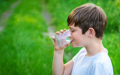 Side view of boy drinking water from glass