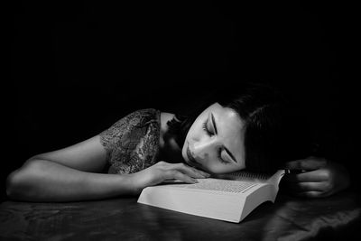 Woman with book sleeping against black background