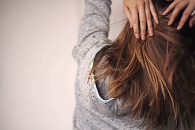 Rear view of young woman standing against wall