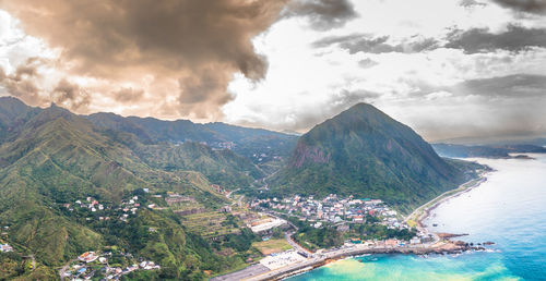 Aerial view of townscape by mountains against sky