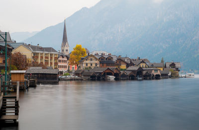 Houses by river and buildings against sky