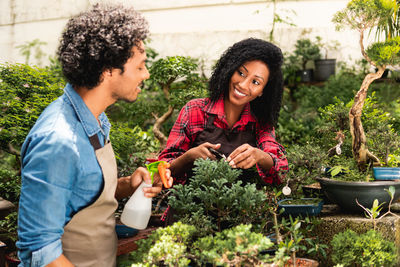 Portrait of smiling friends sitting by plants