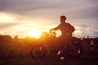 Man sitting on motorcycle against sky