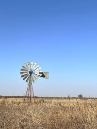 Low angle view of windmill against clear blue sky