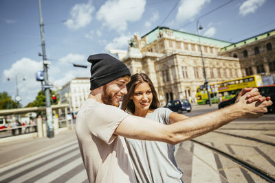 Austria, vienna, happy young couple dancing viennese waltz in front of state opera