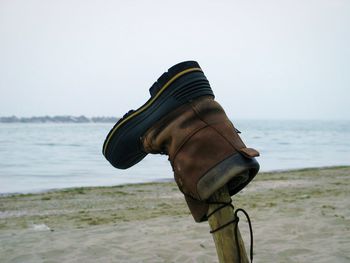 Low angle view of shoes on beach against clear sky