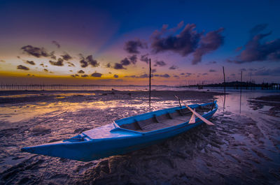 Boats moored on shore against sky during sunset