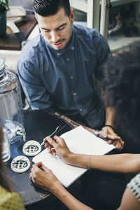 High angle view of workers discussing over notepads in store