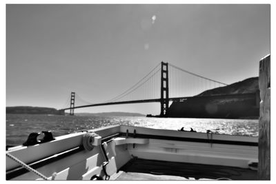 Suspension bridge over sea against clear sky