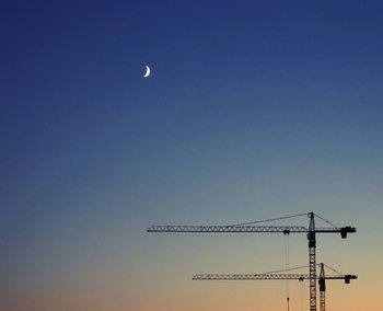 Low angle view of crane against clear blue sky