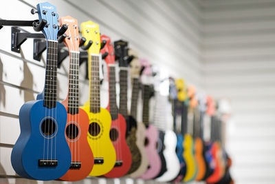 Multicolored acoustic guitars hang in a row in a music store on a white background.