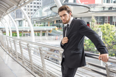 Portrait of confident businessman standing in elevated walkway in city