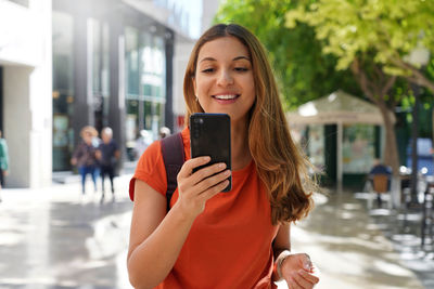 Young smiling woman using mobile phone outdoors