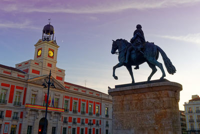 Low angle view of statue of historic building against sky