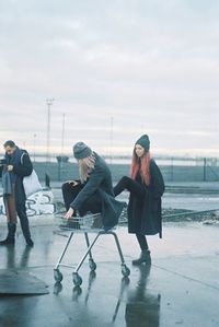 Side view of people sitting on airport runway against sky