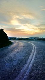 Road by sea against sky during sunset