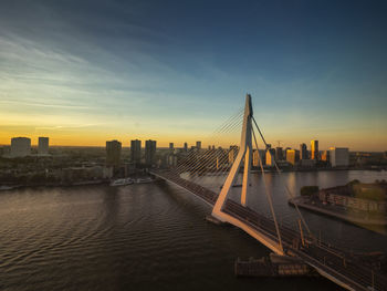 Bridge over river in city against sky during sunset