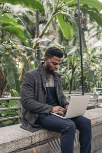 Young man using laptop while sitting outdoors