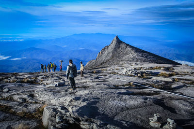 Rear view of woman walking on mountain against sky