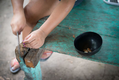 Low section of woman cutting nut on table