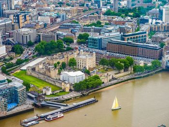 Boat sailing in thames river by buildings in city