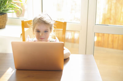Portrait of cute girl using laptop at home
