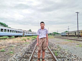 Portrait of man standing on railroad track against sky