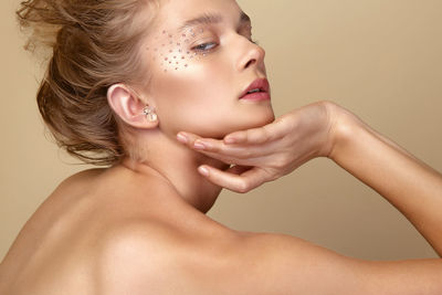 Portrait of young woman with eye make-up against brown background