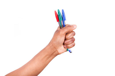 Close-up of hand holding multi colored pencils against white background