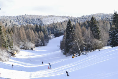 Panoramic view of people skiing on snow covered land