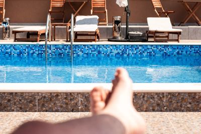 Low section of person resting by swimming pool
