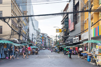 People walking on road against buildings in city