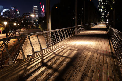 Empty footpath amidst buildings in city at night