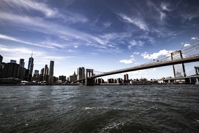 Brooklyn bridge over river with manhattan in background in ny